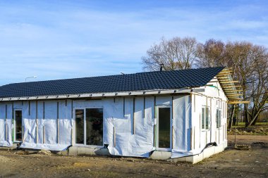 Tamamlanmamış, tek katlı ahşap çerçeveli ev cepheyi bitirmeden önce, mavi gökyüzü arka planı