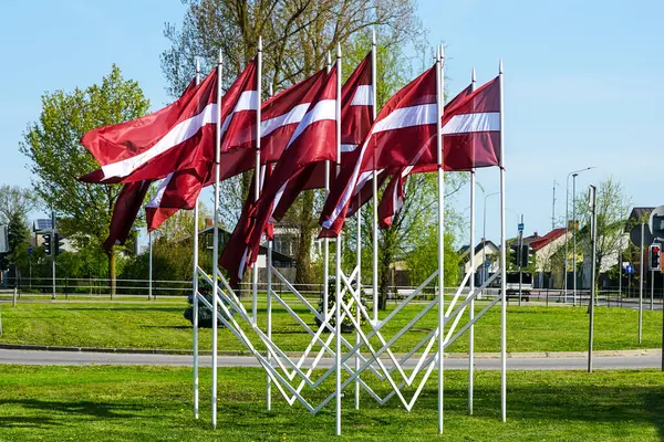 stock image Many national flags of Latvia fluttering in the wind as a decoration of the city during national holidays, blue sky background
