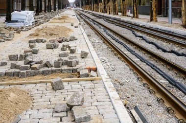 Sokakları yeniden inşa etme manzarası, tahta kapaklı ağaç gövdeleri, yeni değiştirilmiş tramvay rayları, bitmemiş doğal granit kaldırımlar.