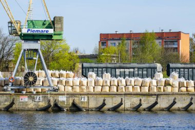 Liepaja, Letonya - 01 Mayıs 2024: Rus tahıl vagonları ve liman kanalı kıyısında gübre balyaları