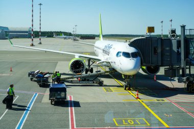 Riga, Letonya - 22 Mayıs 2024: Air Baltic yolcu uçağı Airbus A220-300 RIX Riga havaalanı, bagaj yükleme, havaalanı ekipmanları