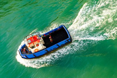 Küçük bir pilot teknesi yeşil Akdeniz sularında yelken açar ve beyaz köpük izi yaratır.