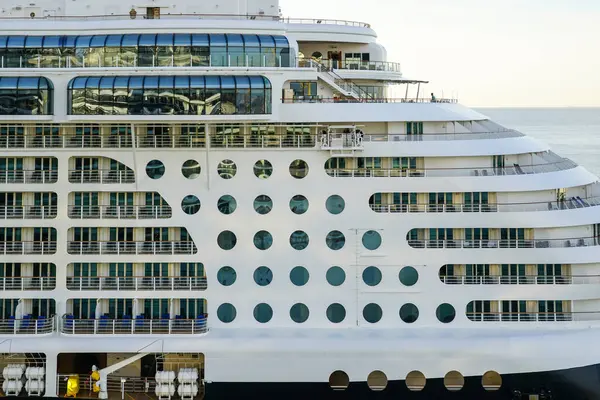 stock image Large multi-deck cruise ship side view fragment with round portholes rows and cabins balconies with railing