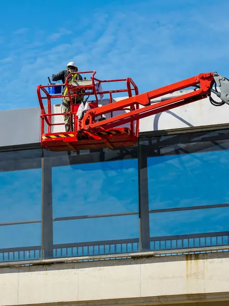 stock image Elevated pedestrian overground crossing tunnel facade painting using a telescopic boom lift with a basket