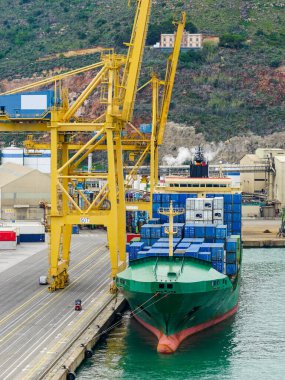 Liman ticari konteynır terminaline büyük bir kargo gemisi yükleniyor.