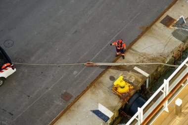 The process of mooring a large cruise ship with a rope at the harbor pier, pulling the rope ashore using a pickup, view from above, ship berthing clipart