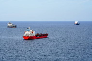 Denizde gemi sevkiyatı, üç farklı yönde hareket eden üç farklı gemi ufukta mavi gökyüzü, nakliye güvenlik kavramı, deniz trafiği.