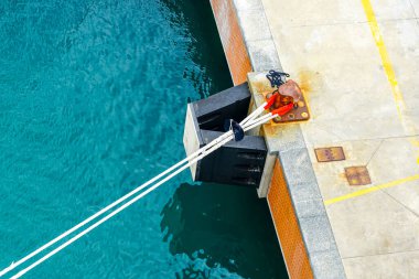 A tense stretched ships thick mooring ropes at the mooring pole of the harbor concrete quay, rope for securing ship, mooring bollard clipart