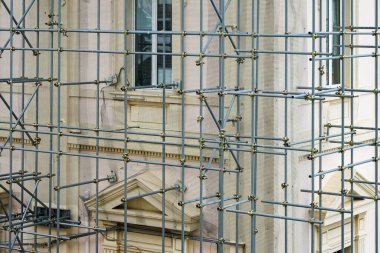 Prefabrik ve konnektörlerin modern tamamlanmamış inşaatı evin ön cephesinde galvanize metal boru iskelesine katıldı.