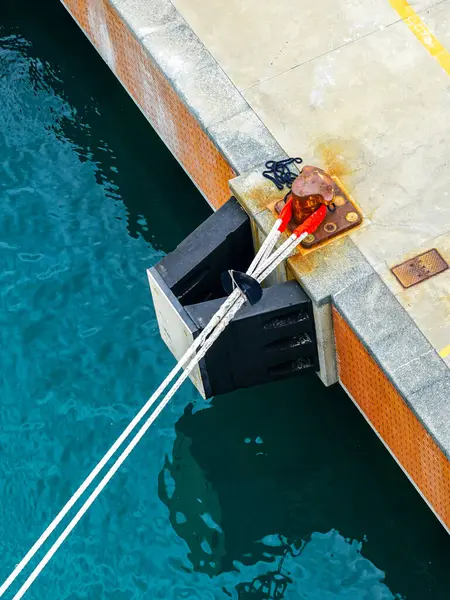 stock image A tense stretched ships thick mooring ropes at the mooring pole of the harbor concrete quay, rope for securing ship, mooring bollard