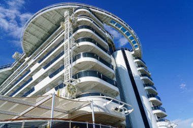 Mavi gökyüzü arka planında kamara balkonları, gemi gövdesi ve güverte temizleme tesisi olan lüks bir yolcu gemisinin kıç tarafında.