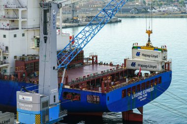 Civitavecchia, Italy- 29 Mayıs 2024: Port vinç Hapag-Lloyd kargo konteynırlarını Livorno Express, IMO 9610157 konteynırına yerleştirdi