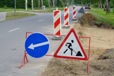 Uyarı ve yön işaretleri ve kırmızı ve beyaz çizgili direklerle sınırlandırılmış yol kenarı onarım alanı, uyarı levhaları dikildi