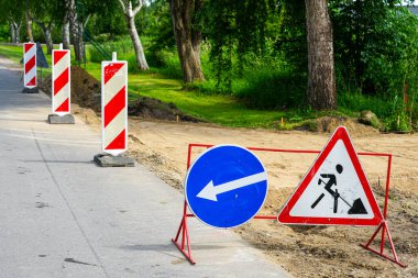 A roadside repair area demarcated by warning and direction road signs and red and white striped posts, warning road signs have been erected clipart