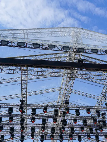 Büyük bir açık hava sahnesinin metal kirişleri ve aydınlatma elementleri, alüminyum konser sahne iskeleti parçaları, sahne ışıklandırması bir kirişe kelepçelenmiş.