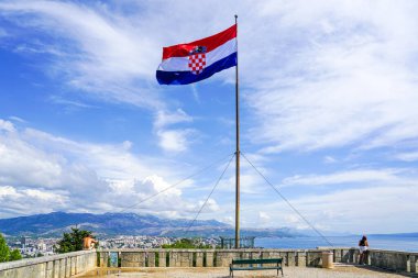Split, Hırvatistan - 20 Eylül 2024: Hırvatistan 'ın Split kentinde uzun bir direkte büyük bir Hırvat bayrağı yakınında bir kadın ve bir erkek