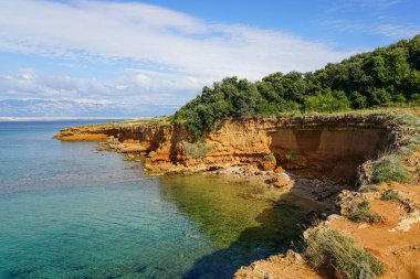 Crvenka plajı, Vir, Hırvatistan, plajın kumu etrafındaki toprağın yoğun kırmızı rengiyle boyanmış, plaj kırmızı bir kayanın altına kazınmış.
