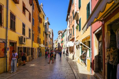 Rovinj, Hırvatistan - 25 Eylül 2024: Eski Rovinj kasabasında renkli binalar ve turistlerle dolu canlı, kaldırımlı bir cadde