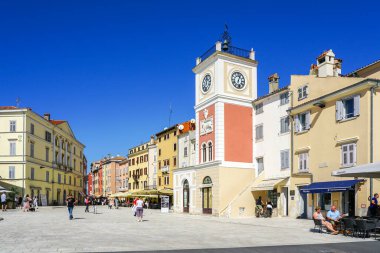 Rovinj, Hırvatistan - 25 Eylül 2024: Saat kulesi ve açık mavi gökyüzü altında tarihi binaları olan Rovinj 'in ana meydanı