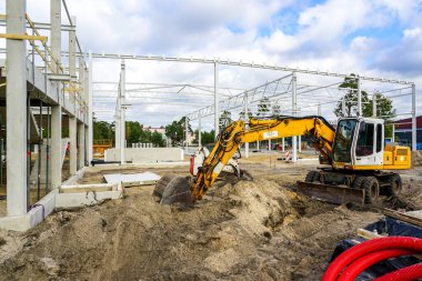 Yeni bir modern fabrikanın inşaat sahası beton ve metal yapı iskeletini güçlendirdi, kazıcılı toprak çalışmaları, kazma kazma kazıları