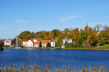 Beyaz kilise kulesi olan Talsi Eski Kasabası 'nın güzel manzarası sonbahar renklerinde ağaçlar mavi gökyüzü, Letonya, Avrupa' da küçük tarihi bir kasaba