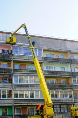 Teleskopik eklem kaldırma platformu kullanarak bir apartmanın güçlendirilmiş beton panellerindeki dikişlerin ve çatlakların mühürlenmesi