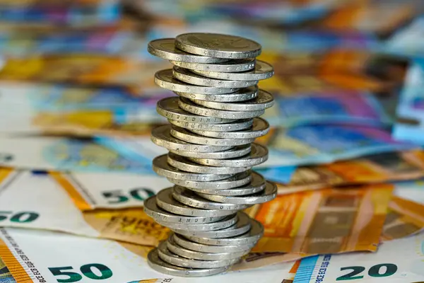 Avro banknotlarının arkaplanındaki iki avroluk dengesiz piramit, durgun ekonomi kavramı, istikrarsız madeni paralar yığını, gelecekteki istikrarsızlık