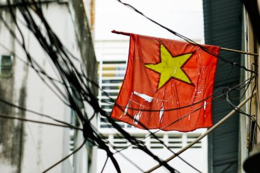 Elektrik kablolarına dolanmış sarı yıldızlı paçavra bir Vietnam bayrağı Ho Chi Minh City, Vietnam 'da bir sokak sahnesi.