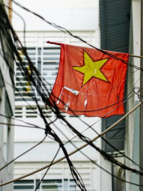 Elektrik kablolarına dolanmış sarı yıldızlı paçavra bir Vietnam bayrağı Ho Chi Minh City, Vietnam 'da bir sokak sahnesi.