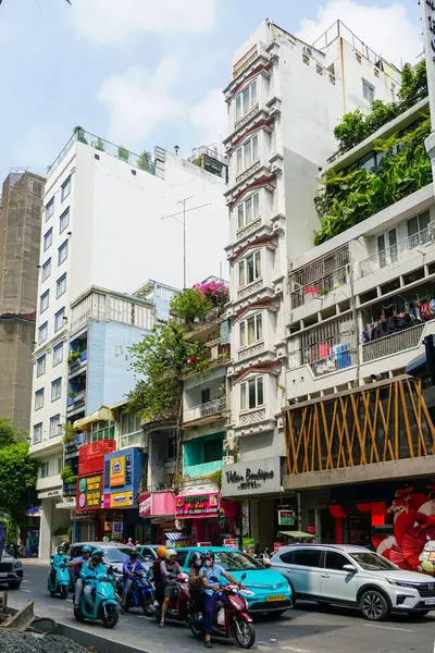 Ho Chi Minh Şehri, Vietnam- 16 Mart 2025 Dar Binalı, Şehir Yeşilliği ve Scooter 'lı Vibrant City Street Scene