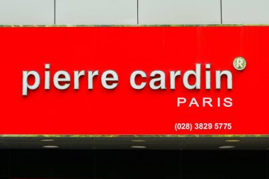 Ho Chi Minh City, Vietnam- 16 Mart 2025 Pierre Cardin Paris moda markasının canlı kırmızı paneli üzerinde kontak numarası ve logosu