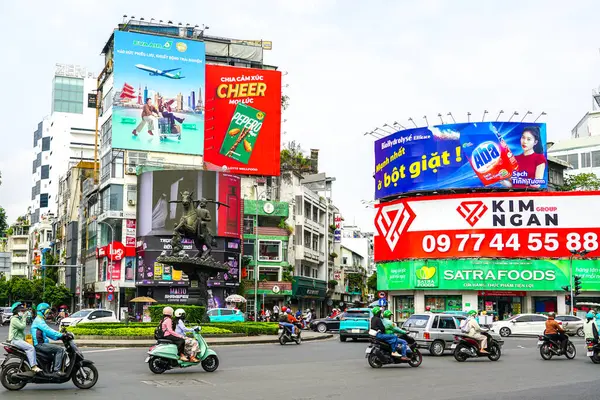 Ho Chi Minh Şehri, Vietnam - 16 Mart 2025: Renkli Billboardlar, Scooterlar ve Bir Anıtın Çevresindeki Şehir Yaşamı ile Dolu Saigon Kavşağı