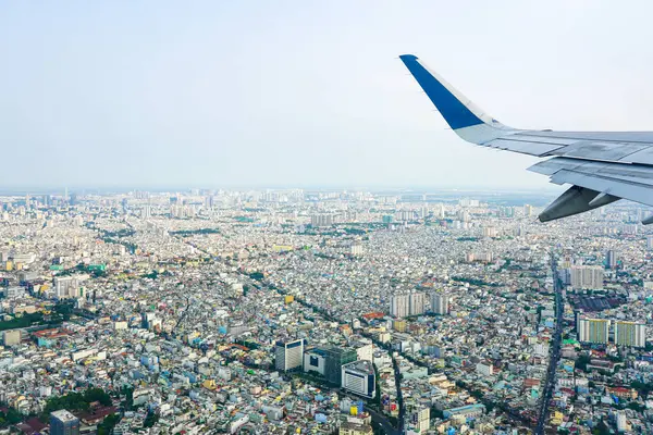 Ho Chi Minh Şehri, Vietnam 'ın yoğun şehri üzerinde bulunan uçak kanadı açık mavi gökyüzü altında binlerce bina gösteriyor.
