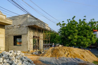Vietnam 'da iskele, tuğla, çakıl yığınları ve elektrik kablolarının bulunduğu tuğla ev inşaatı.