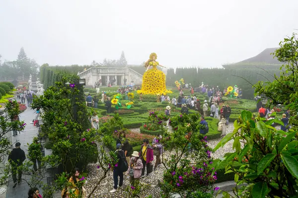 Ba Na Hills, Vietnam-17 Mart 2025: Turistler, sisli bir günde dev sarı çiçekli elbise heykeliyle çiçek bahçesini keşfetti
