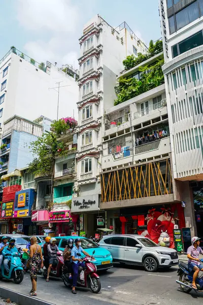 Ho Chi Minh Şehri, Vietnam- 16 Mart 2025 Dar Binalı, Şehir Yeşilliği ve Scooter 'lı Vibrant City Street Scene