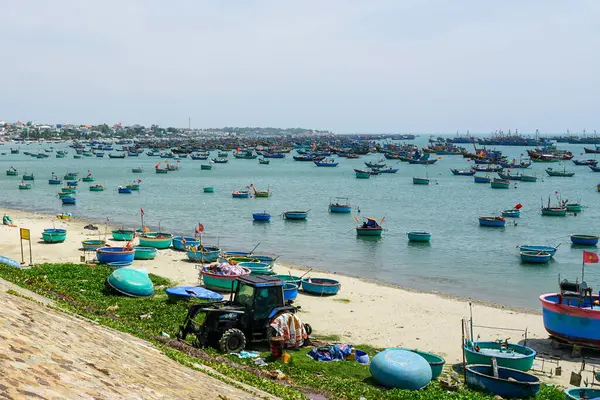 Vietnam 'ın hareketli limanı Mui Ne balıkçı köyünün turkuaz sularına demir atmış yuvarlak sepet tekne ve balıkçı teknelerinin canlı görüntüsü.