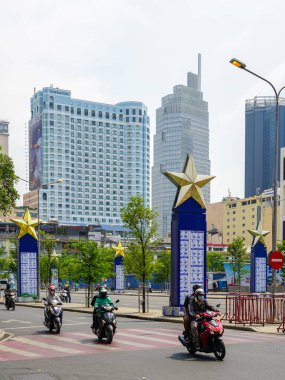 Ho Chi Minh City, Vietnam - 16 Mart 2025: Motosiklet trafiği, altın yıldız sütunları ve Sheraton Oteli ile yüksek gökdelenli bir gökyüzüne karşı