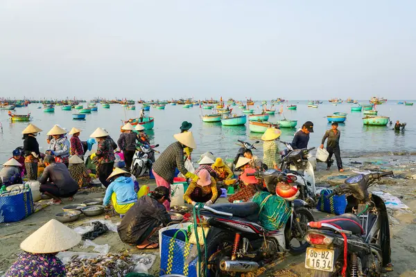 Mui Ne, Vietnam- 22 Mart 2025: Vietnam 'daki hareketli kıyı pazarı sahnesi yerel satıcıların renkli teknelerle dolu bir limanın yakınında taze deniz ürünleri sattığı yer.