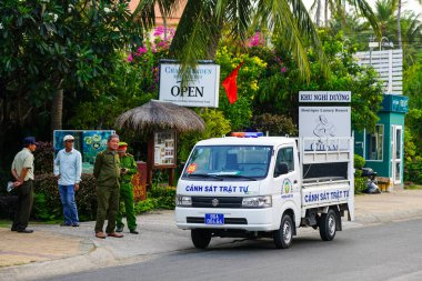Mui Ne, Vietnam- 21 Mart 2025: Üniformalı belediye memurları ve bir polis kamyonu bir butik tatil köyünün yakınına konuşlandırıldı.
