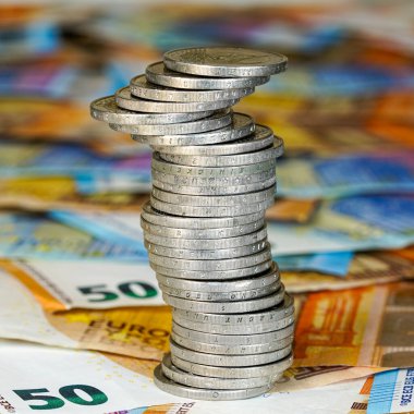 Bu fotoğraf, avro banknotlarının üzerine yerleştirilmiş, finans, denge ve maddi istikrarın kırılgan doğasını ön plana çıkaran, gümüş avroluk bir kuleyi gösteriyor.