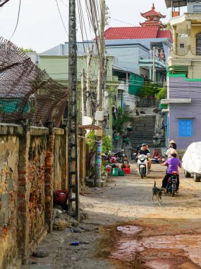 Mui Ne, Vietnam- 22 Mart 2025: Mui Ne 'de günlük hayatın scooterlarla, satıcılarla, yerlilerle ve arka planda bir tapınakla sergilendiği canlı bir sokak