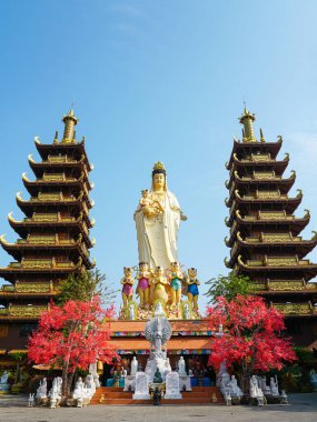 Mui Ne, Vietnam 'daki çarpıcı bir Budist tapınağında altın çatılı ikiz pagodalar ve canlı kırmızı ağaçlarla çevrili büyük bir Quan Am heykeli bulunuyor.