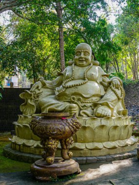 Dalat, Vietnam- 24 Mart 2025: Huzurlu bir Buda heykeli Vietnam manzaralı Pongour Şelalesi yakınlarındaki bir orman türbesinde huzur içinde duruyor.