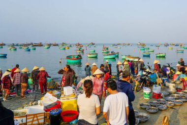 Mui Ne, Vietnam- 22 Mart 2025: Yerel halk, balıkçıların geleneksel sepet tekneleriyle taze deniz ürünleriyle dönmeleri üzerine canlı bir sabah pazarı olan Mui Ne 'de toplandı
