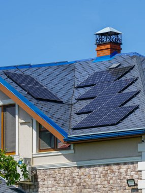 Şık bir ev, temiz enerji kullanımını ön plana çıkaran, mavi kiremitli çatısına kurulmuş birden fazla güneş paneli içerir.