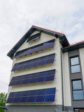 Ön cephesinde dikey olarak sıralanmış güneş panelleri olan çok katlı bir bina, temiz, yenilenebilir güneş enerjisi çözümlerini teşvik ediyor.