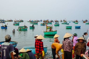 Mui Ne, Vietnam- 22 Mart 2025: Yerel balıkçılar denizden dönen geleneksel yuvarlak tekneler olarak erkenden kıyıda toplandılar