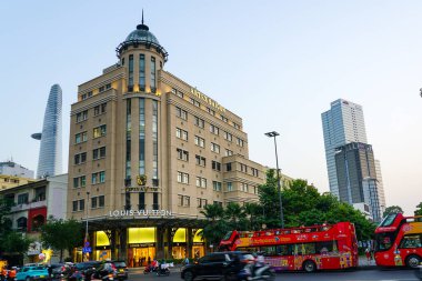 Ho Chi Minh City, Vietnam- 26 Mart 2025: Opera View binası, Louis Vuitton mağazası ve kırmızı tur otobüsleriyle akşam sokak sahnesi