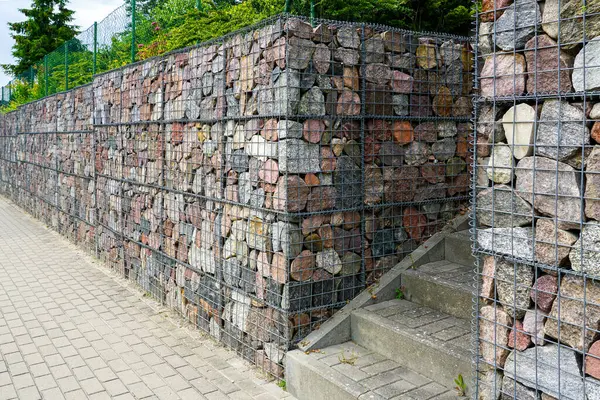 Gabion rengarenk taşlarla dolu duvarlar peyzajlı bir şehir yolunda beton bir merdiven.